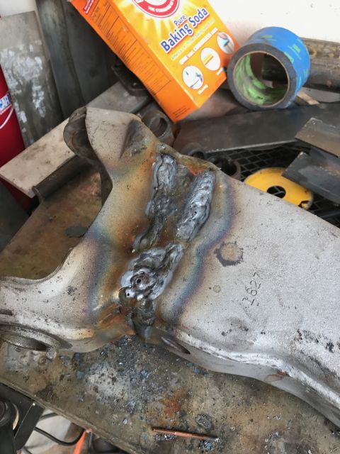 1996 Ford Bronco - A close-up view of a metal automotive part that has been welded. The part is dusty and shows discoloration from the welding process. A box…