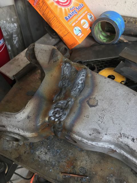 1996 Ford Bronco - A close-up view of a metal automotive part that has been welded. The part is silver with colorful heat discoloration around the welds and h…