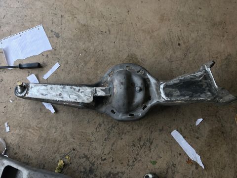 1996 Ford Bronco - A metal differential housing with a bolted cover is shown on a concrete floor. One end of the housing has a welded bracket, and the other e…