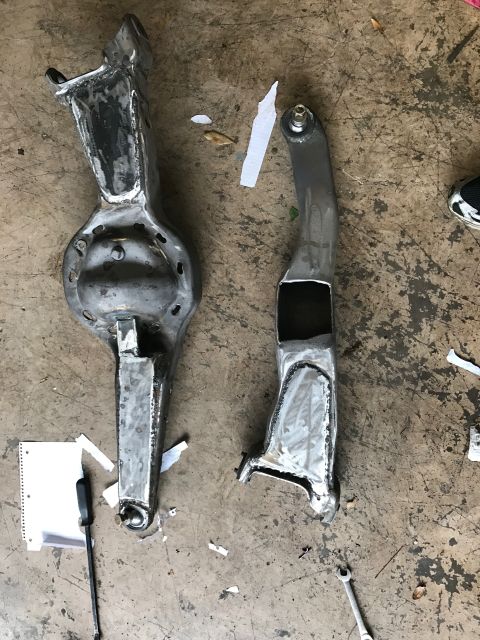 1996 Ford Bronco - Two custom-fabricated metal suspension components are laid out on a concrete floor. One component is a differential housing with a long tra…