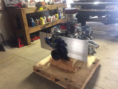 1982 Ford Bronco - A V8 engine with chrome headers and a red air filter sits on a wooden pallet in a garage. A workbench with tools and supplies is visible in…