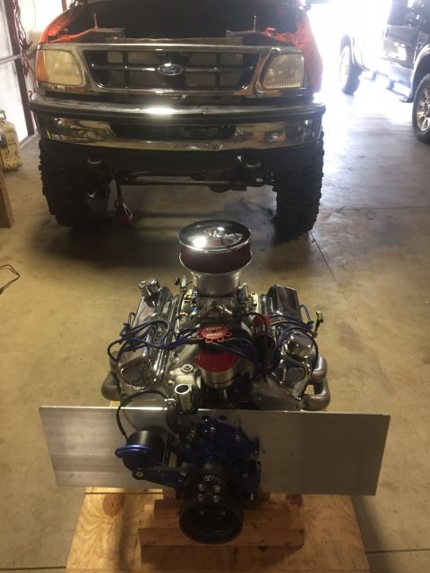 1982 Ford Bronco - A custom V8 engine with chrome accents and a red air filter sits on a wooden pallet in front of a lifted Ford truck. The engine is mounted…