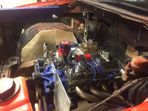 1982 Ford Bronco - The engine bay of a classic vehicle, likely a Ford Bronco, is shown with the engine partially installed. Various engine components, includi…