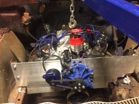 1982 Ford Bronco - A close-up view of a V8 engine being installed in a vehicle, likely a Ford Bronco, with a blue water pump and red MSD distributor visible.…