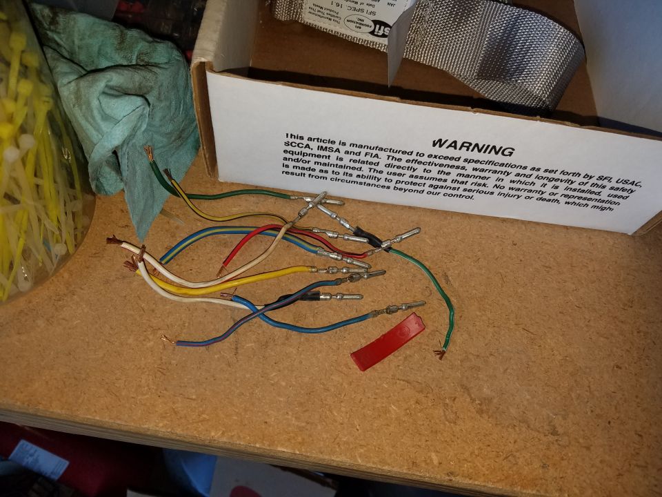 Wires with connectors, warning label, green cloth, and zip ties on a wooden surface.