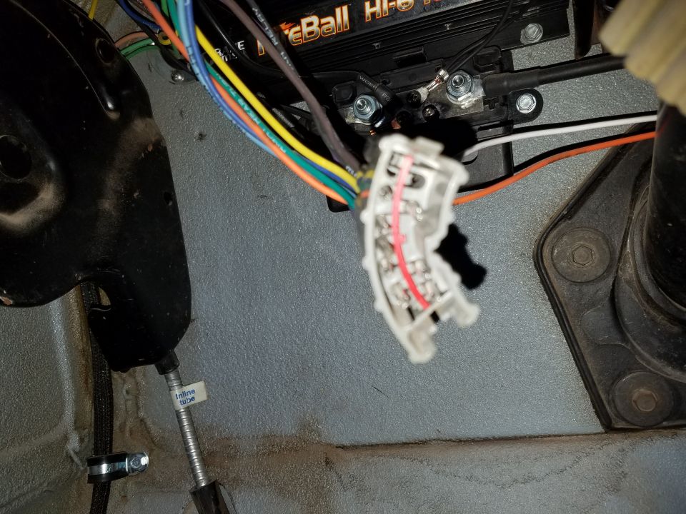 Automotive wiring harness and connector with red and silver wires connected to a black electronic module.