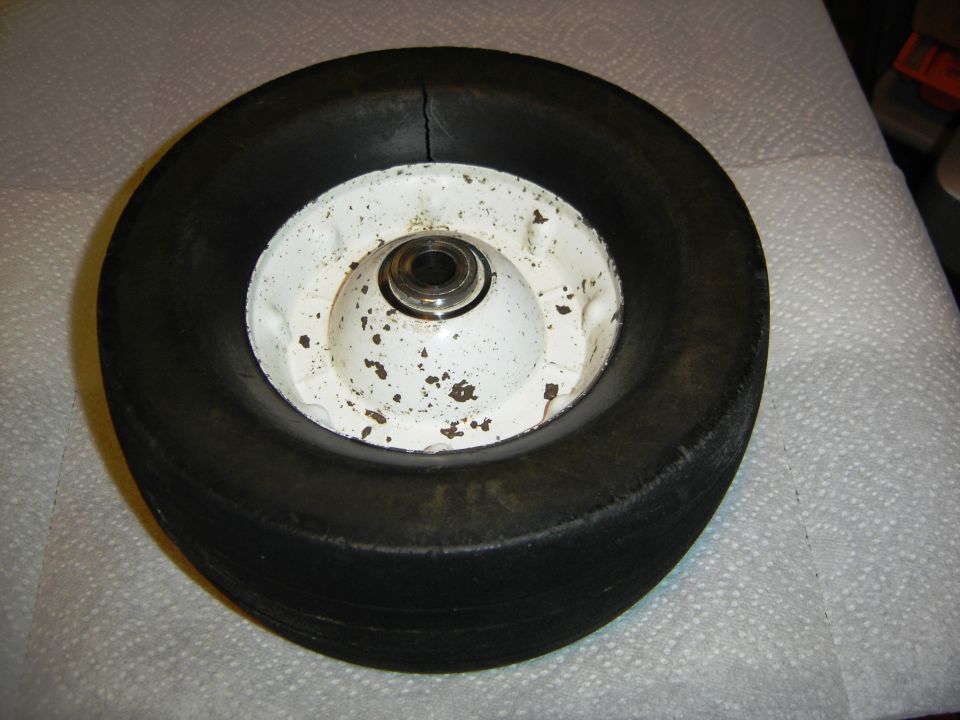 Wheel with black tire and white rim, showing a crack in the tire.