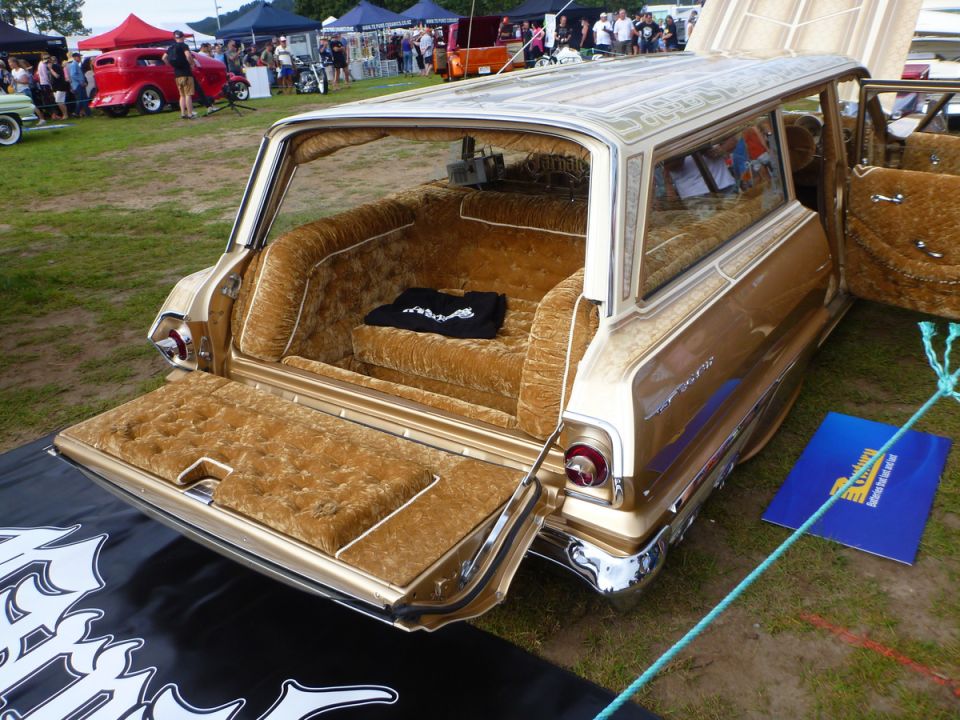 Gold custom station wagon with plush velour interior and open tailgate.