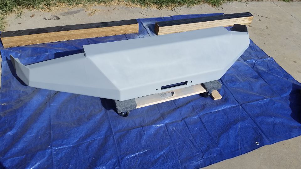 aftermarket bumper with winch cutout, primed gray, on blue tarp