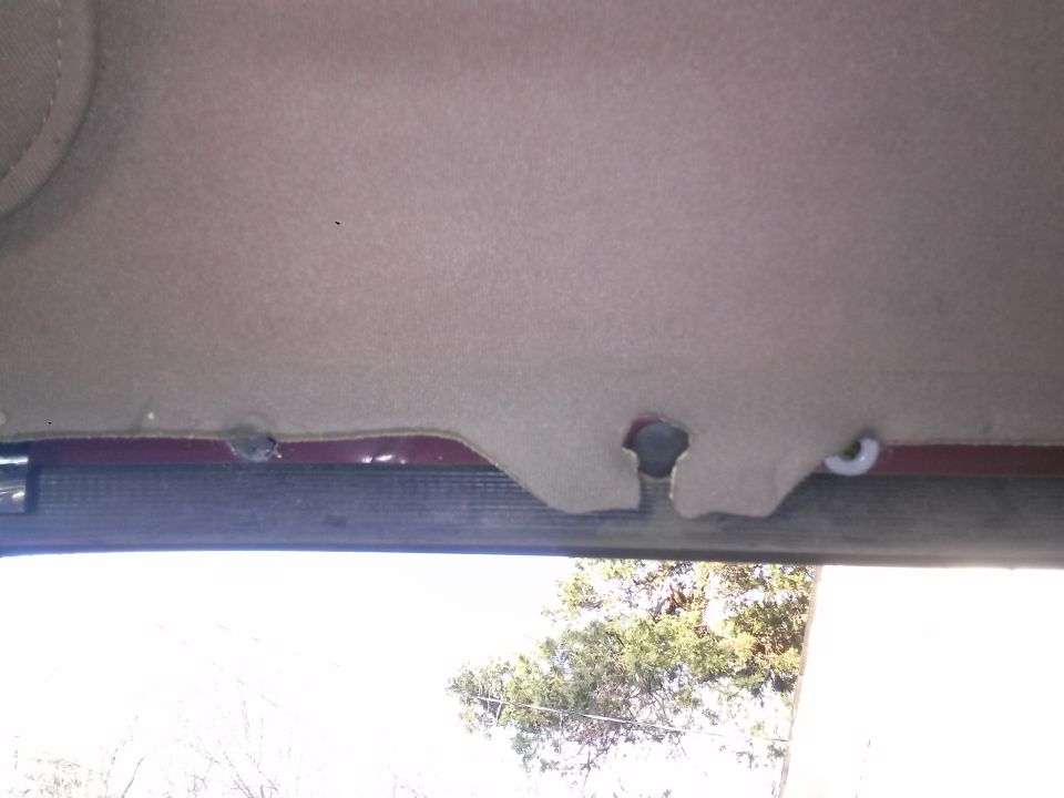 Detached headliner near windshield with visible hole and clip.