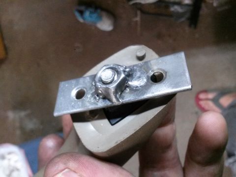 1996 Ford Bronco - A close-up shot of a metal bracket with a bolt and nut, attached to a beige plastic component. The bracket appears to have been welded, and…