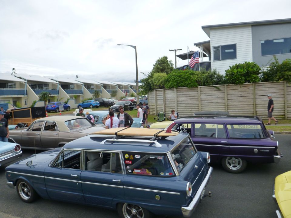 Several classic cars parked on a street, including a blue and a purple station wagon.