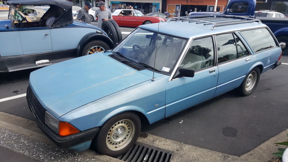 Light blue station wagon parked next to a vintage light blue convertible.
