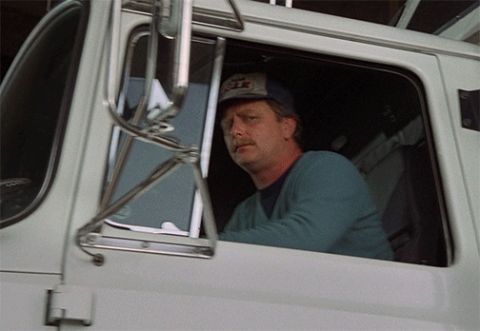 1995 Mercury Grand Marquis - A man wearing a blue and grey baseball cap and a teal sweater looks out the driver's side window of a white truck. The truck's large side m…