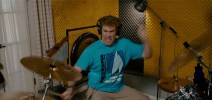 1995 Mercury Grand Marquis - A man wearing headphones is energetically playing a drum set in a room with yellow soundproofing foam on the walls.