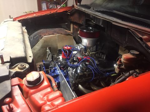 1982 Ford Bronco - The engine bay of a classic vehicle, likely a Ford Bronco, is shown with an orange exterior. The engine features a chrome air cleaner, blue…