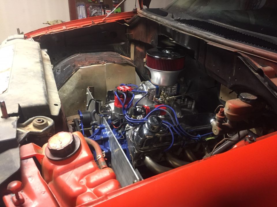 Engine bay of a classic vehicle with custom modifications, including chrome and blue accents.