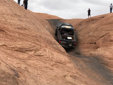 1991 Ford Bronco - A dark blue 1991 Ford Bronco is descending a steep, rocky incline. The vehicle has its rear spare tire mounted and appears to be off-roadin…
