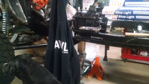 1985 Jeep CJ7 - A black sweatshirt with "AVL" and "offroad" printed on it hangs in front of a partially assembled vehicle chassis. The vehicle appears to b…