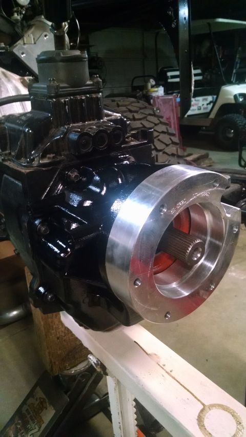 1985 Jeep CJ7 - A close-up view of a black transmission or transfer case with a silver adapter plate attached to the front. The adapter plate has several b…