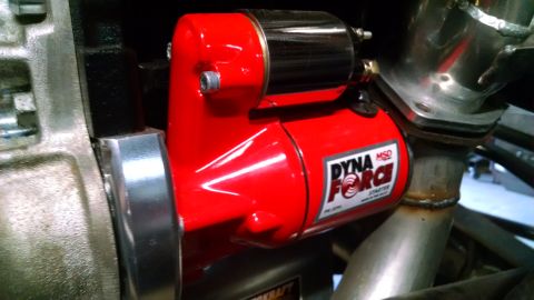 1985 Jeep CJ7 - A bright red MSD Dyna-Force starter is mounted to a vehicle's engine block, with polished metal exhaust pipes visible nearby.