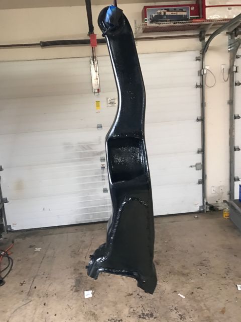 1996 Ford Bronco - A black painted vehicle part, possibly a suspension component, is hanging from a hook in a garage. The part has a glossy finish and appears…