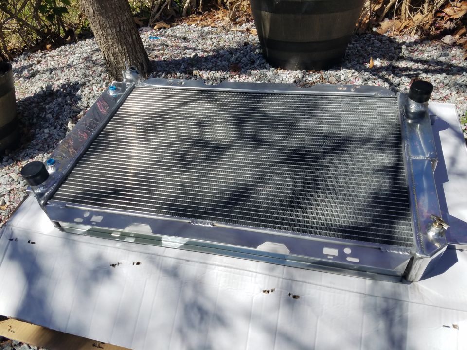 New aluminum radiator with blue and black caps, displayed outdoors.