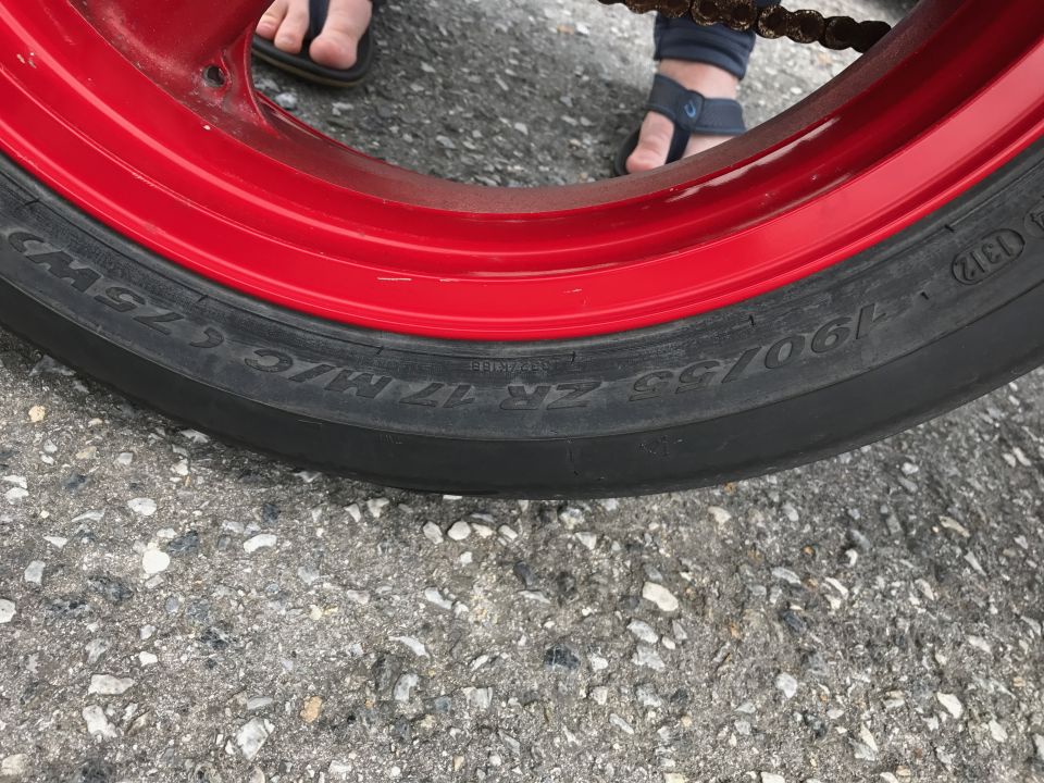 Motorcycle tire with red rim and visible size markings.