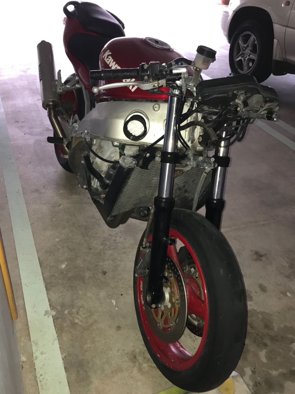 Red and silver Kawasaki motorcycle front view, partially disassembled.