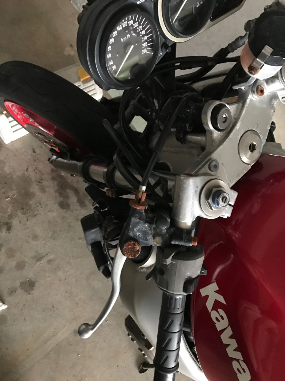Kawasaki motorcycle top view showing handlebars, speedometer, and front forks in a garage