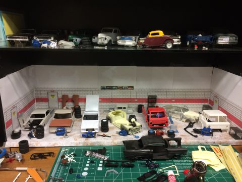 1989 Ford Bronco - A collection of model car kits and parts are displayed in a diorama of a garage setting.