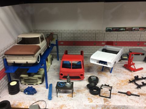 1989 Ford Bronco - A model car garage scene displays various unfinished vehicle bodies and parts, suggesting a build or restoration project.