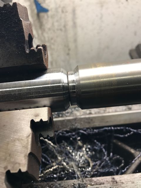 1996 Ford Bronco - A metal shaft is being machined on a lathe, creating metal shavings.