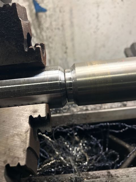 1996 Ford Bronco - Machining a metal shaft on a lathe, with metal shavings visible.