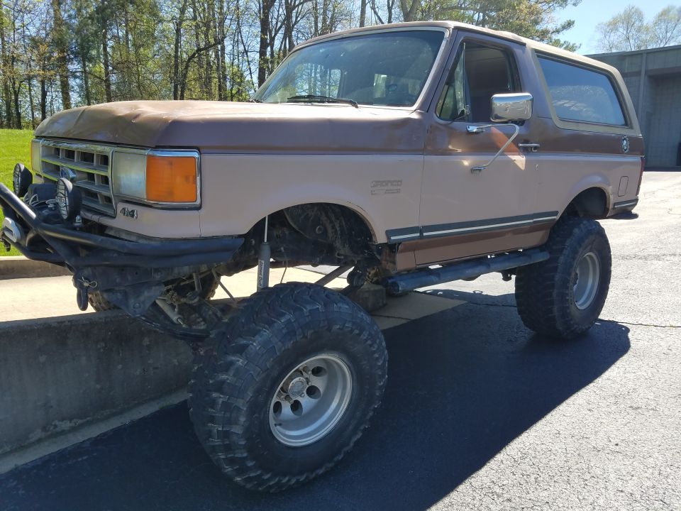 1988 Ford Bronco lifted with large off-road tires and aftermarket bumper