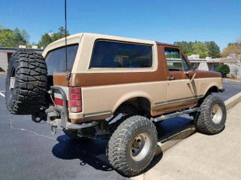 1988 Ford Bronco - This modified Ford Bronco features a lifted suspension and large off-road tires, with a two-tone paint scheme.