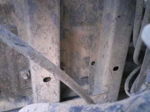 1996 Ford Bronco - Undercarriage view showing frame rails and wiring harness, covered in dirt and grime.