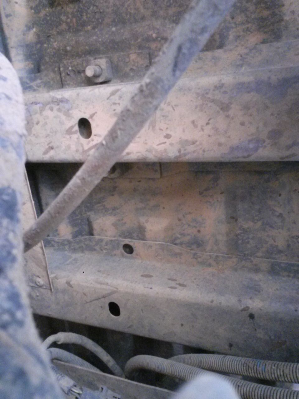 Close-up of dirty vehicle frame with visible bolts and hoses