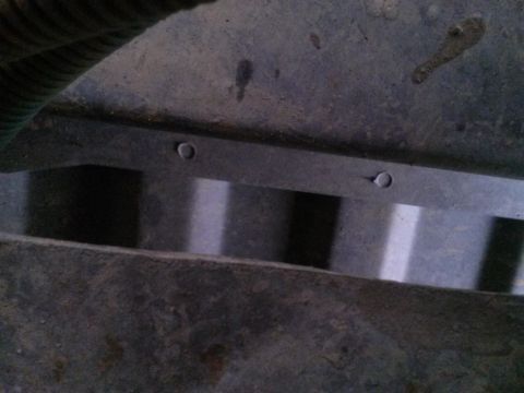 1996 Ford Bronco - Close-up view of an underbody component with visible bolts and a green hose.