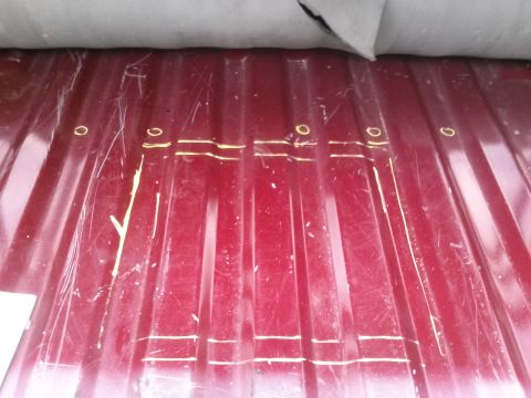 1996 Ford Bronco - A close-up view of a red metallic surface marked with yellow lines and circles, suggesting a part of a vehicle's body or undercarriage.