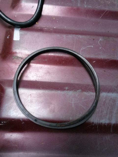 1996 Ford Bronco - A close-up of a fuel float seal ring is shown against a red, textured background.
