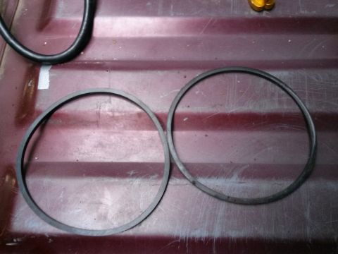 1996 Ford Bronco - Two rubber gaskets, likely for a fuel float replacement, are shown side-by-side on a red surface.