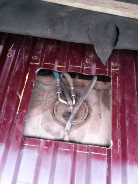 1996 Ford Bronco - The fuel tank sender unit is visible after cutting an access hole in the vehicle's floor pan.