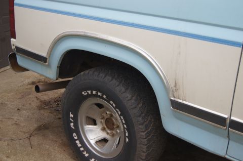 1986 Ford Bronco - Close-up of the rear wheel well and side panel of an older pickup truck.