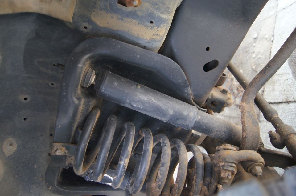 Close-up of a vehicle's front suspension with a coil spring and shock absorber