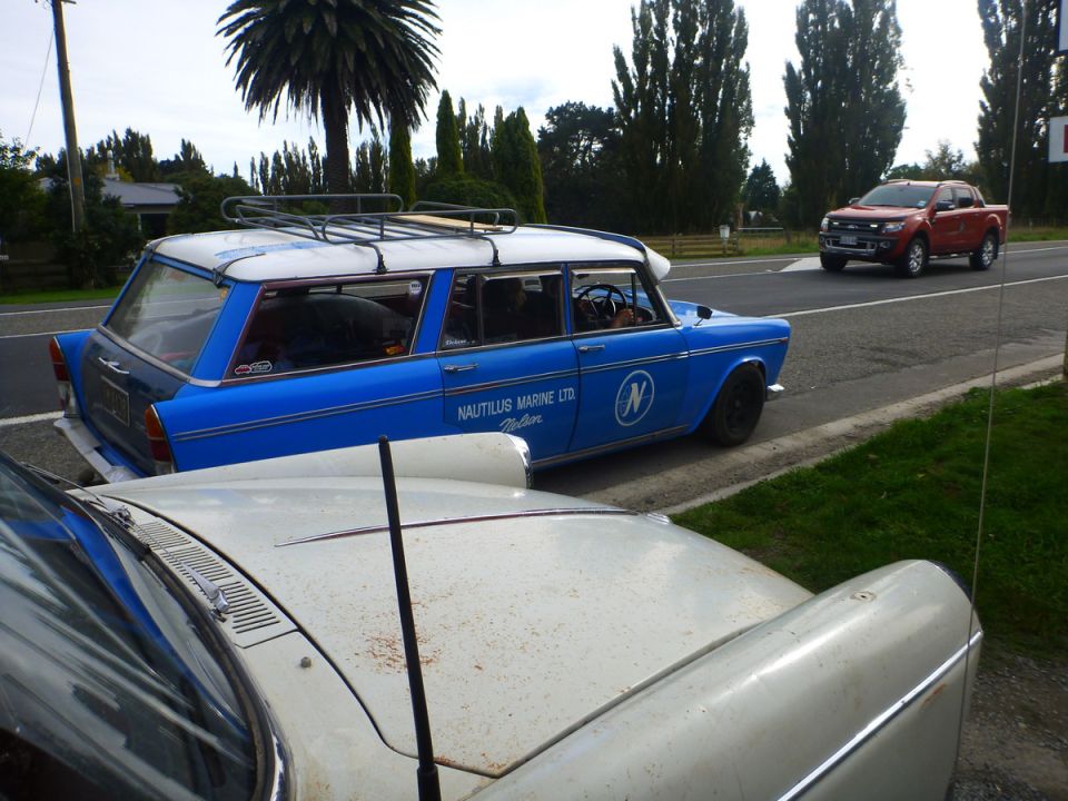 Blue station wagon with white roof and roof rack, side view, parked next to a white car
