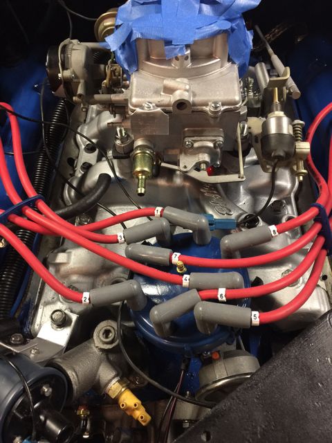 1978 Ford Bronco - Close-up view of an engine's carburetor and spark plug wires, with some parts covered in blue tape.
