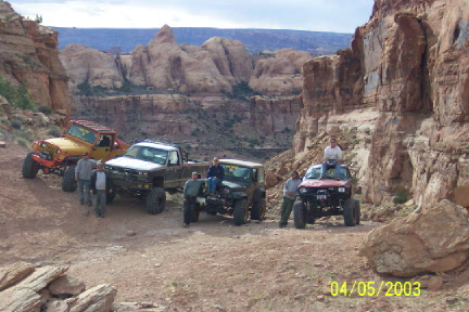 1979 Ford Bronco - Several modified off-road vehicles are stopped on a rocky trail in a scenic canyon landscape.