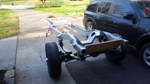 1994 Ford Bronco - Vehicle frame undergoing restoration, with a black SUV parked nearby.
