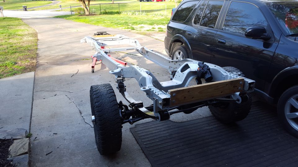 Vehicle frame on jack stands with a black SUV in the background